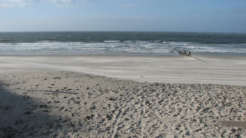 Weiter Nordseestrand mit zwei Menschen am Wasser